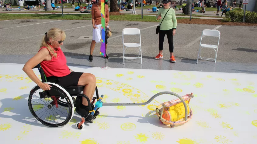 A wheelchair user participates in our &quot;Art for All&quot; activity, which allows disabled patrons as well as children participate in a large collaborative street painting.